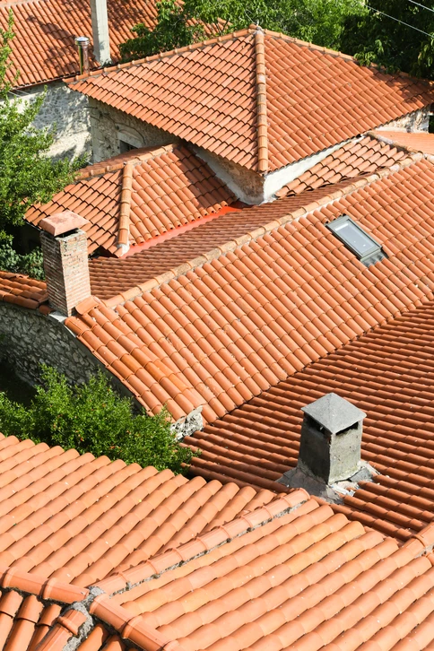 Couvreur zingueur sur un toit en travail de zinguerie, portant casque de sécurité jaune et équipement professionnel, en train de mettre en place ou travailler des éléments de zinguerie (gouttières, descentes, traités en zinc ou matériaux similaires) sur une structure de bâtiment. Scène professionnelle et sécurisée, en conditions réelles de chantier.